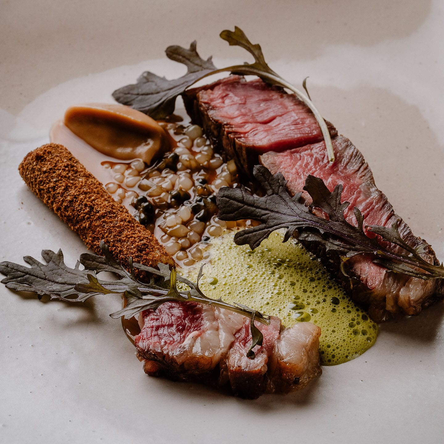 RM Hereford Beef rib with fire-pit leek, alliums and mustard, presented carefully on a white dish